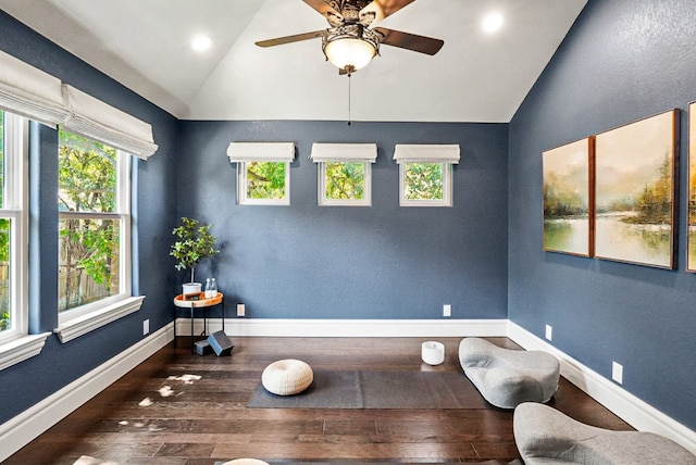 living area with ceiling fan, hardwood / wood-style floors, baseboards, and vaulted ceiling