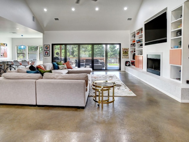 living room with high vaulted ceiling, built in shelves, concrete floors, and a wealth of natural light