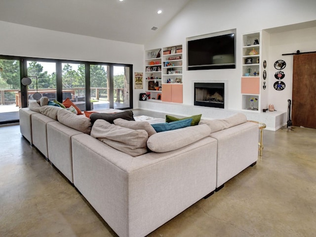 living room featuring high vaulted ceiling, built in shelves, and a barn door