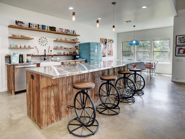 kitchen with pendant lighting, sink, stainless steel dishwasher, stainless steel counters, and a breakfast bar area