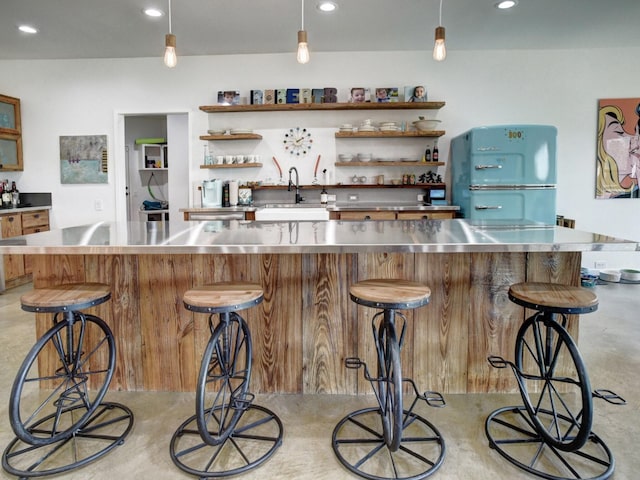 bar featuring fridge, stainless steel counters, and sink