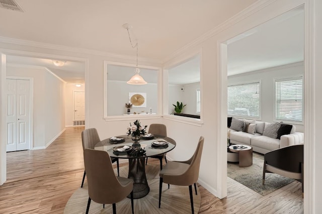 dining area with ornamental molding and light hardwood / wood-style floors