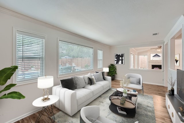 living room featuring ceiling fan, hardwood / wood-style flooring, plenty of natural light, and ornamental molding