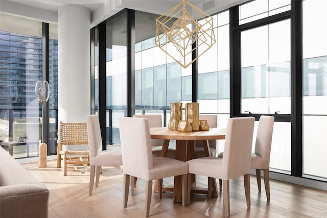 dining room with a healthy amount of sunlight, wood-type flooring, an inviting chandelier, and floor to ceiling windows