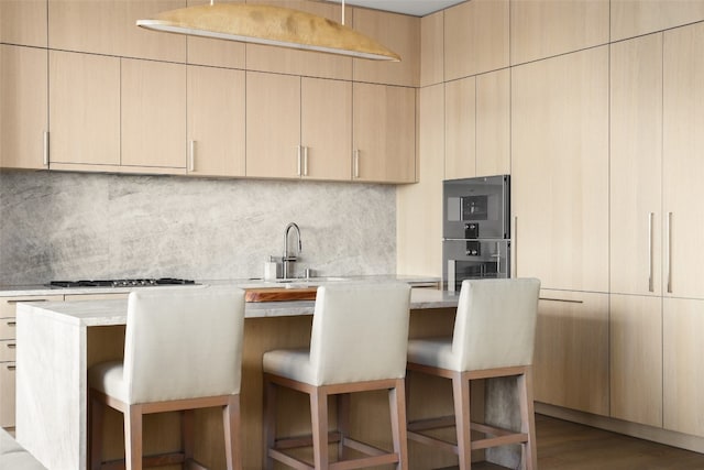 kitchen with gas stovetop, a breakfast bar, hardwood / wood-style flooring, and stainless steel double oven