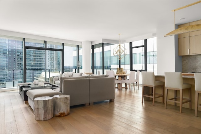 living room featuring light hardwood / wood-style floors, a notable chandelier, a wealth of natural light, and a wall of windows