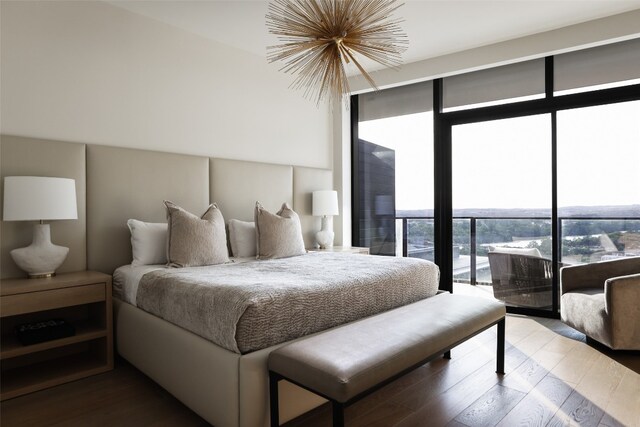 bedroom featuring expansive windows, a notable chandelier, hardwood / wood-style flooring, and access to outside