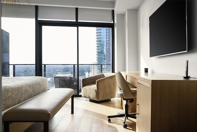 bedroom with light hardwood / wood-style flooring, multiple windows, and a wall of windows