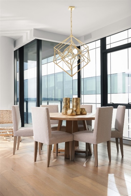 dining area with a wealth of natural light, hardwood / wood-style floors, an inviting chandelier, and expansive windows