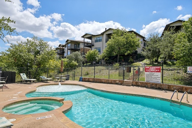 view of pool featuring pool water feature and a hot tub