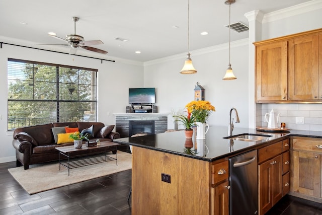 kitchen featuring backsplash, sink, ceiling fan, ornamental molding, and an island with sink