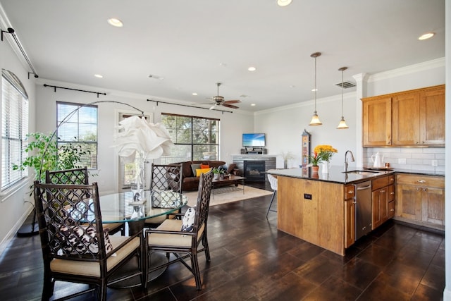 kitchen with stainless steel dishwasher, a wealth of natural light, ceiling fan, sink, and hanging light fixtures