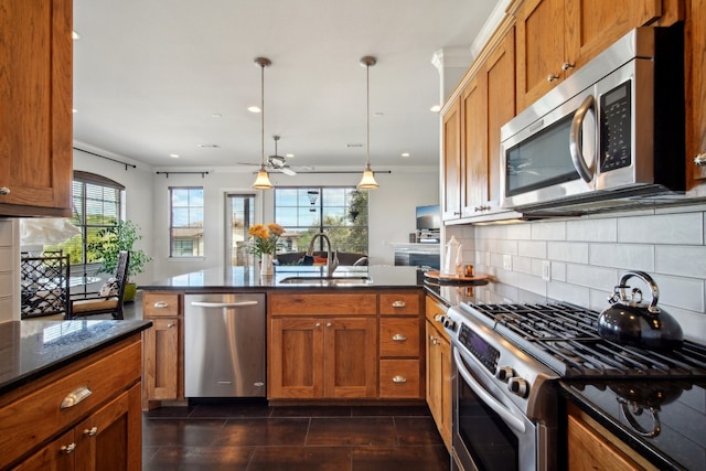 kitchen with backsplash, sink, hanging light fixtures, kitchen peninsula, and stainless steel appliances