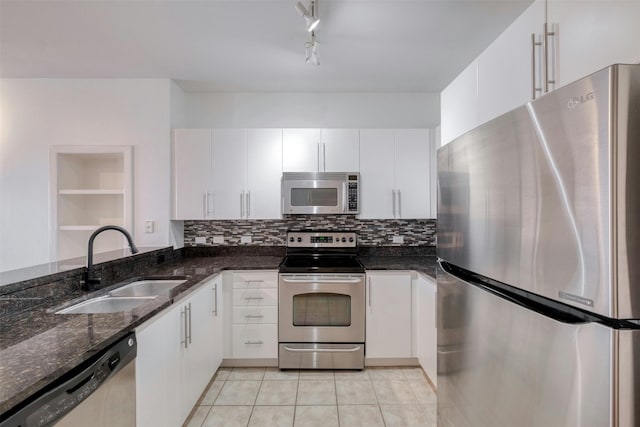 kitchen with appliances with stainless steel finishes, dark stone countertops, white cabinetry, and sink