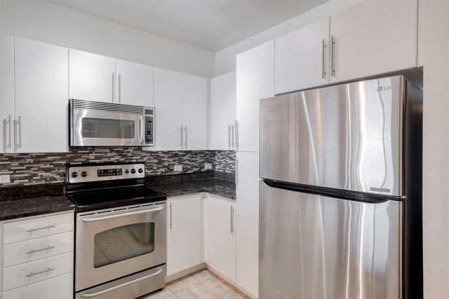 54 Rainey St Unit 1015, Austin, TX 78701 - kitchen featuring appliances with stainless steel finishes, decorative backsplash, white cabinets, dark stone counters, and light tile patterned floors