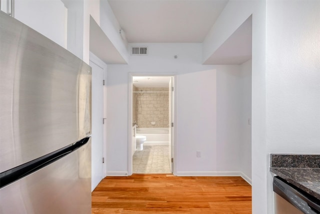 interior space featuring dark stone countertops, light hardwood / wood-style floors, and appliances with stainless steel finishes