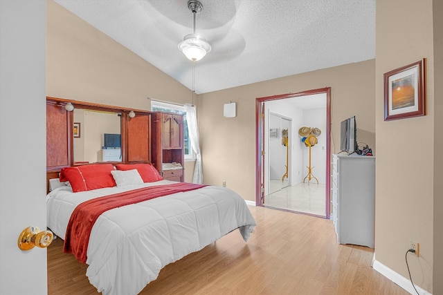 bedroom featuring ceiling fan, a textured ceiling, light hardwood / wood-style flooring, and vaulted ceiling