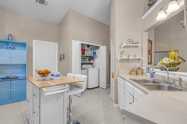 kitchen with a textured ceiling, washer and dryer, sink, white cabinets, and hanging light fixtures