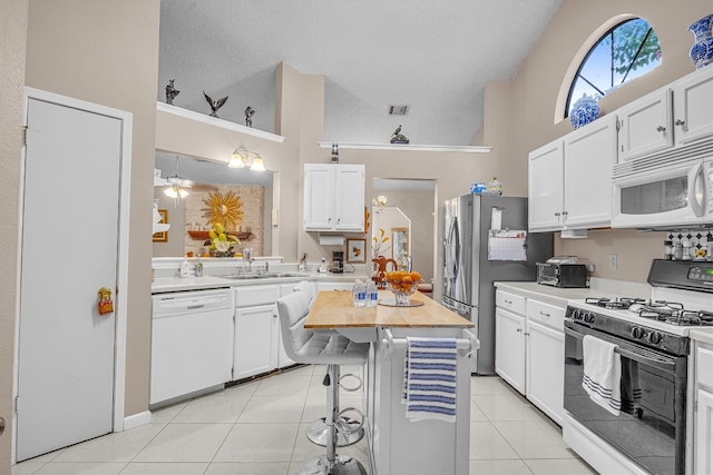 kitchen with high vaulted ceiling, white cabinets, white appliances, and a breakfast bar