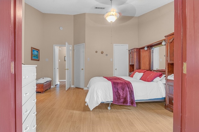 bedroom featuring light hardwood / wood-style floors, a towering ceiling, and ceiling fan