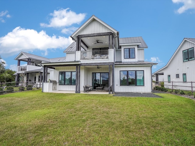 back of property with a balcony, a patio, ceiling fan, and a lawn