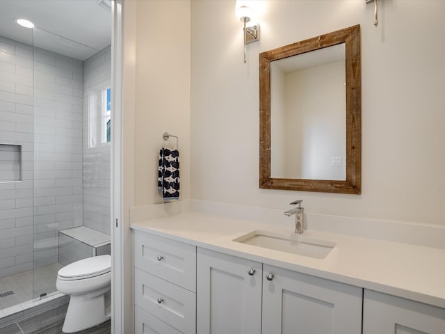 bathroom with walk in shower, vanity, and toilet