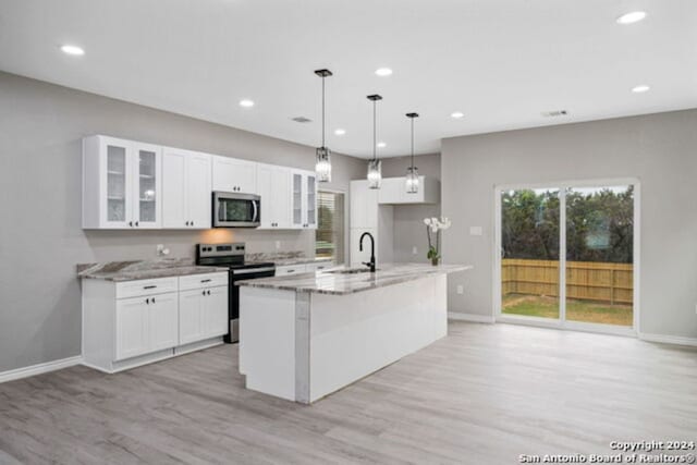 kitchen featuring sink, light wood-type flooring, light stone countertops, appliances with stainless steel finishes, and white cabinetry