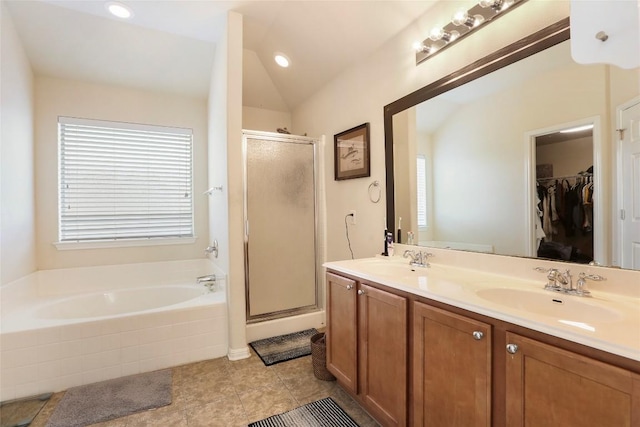 bathroom with a shower stall, a garden tub, double vanity, a spacious closet, and vaulted ceiling