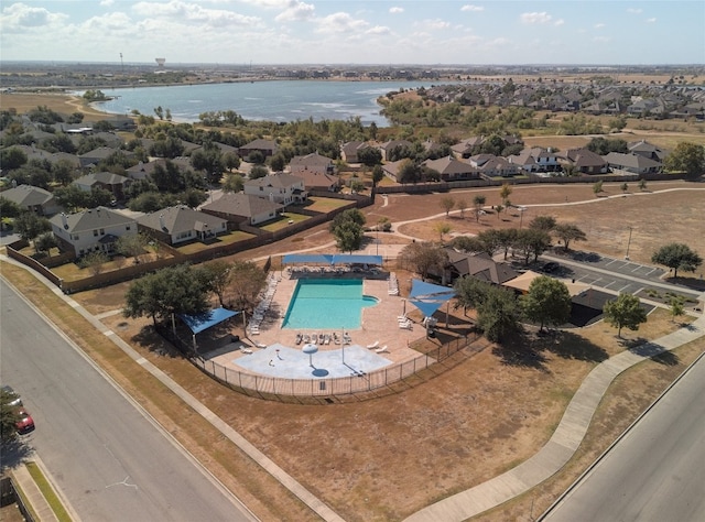 aerial perspective of suburban area featuring a pool and a large body of water