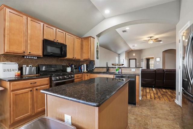 kitchen with appliances with stainless steel finishes, lofted ceiling, arched walkways, a peninsula, and ceiling fan