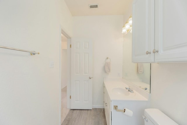 bathroom with hardwood / wood-style floors, vanity, and toilet