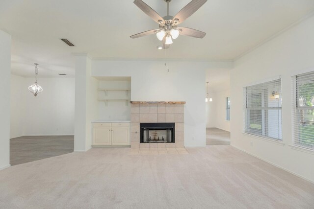 unfurnished living room with a fireplace, ornamental molding, ceiling fan, and light colored carpet