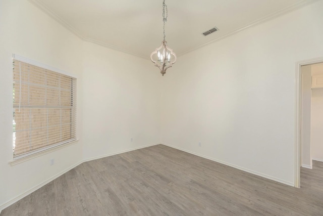 empty room with ornamental molding, wood-type flooring, and an inviting chandelier