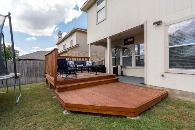 deck featuring a trampoline, outdoor lounge area, and a yard