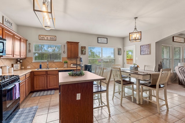 kitchen featuring pendant lighting, sink, tasteful backsplash, black gas range, and a center island