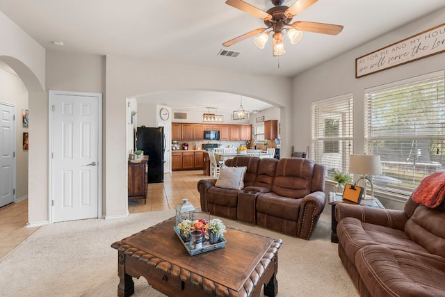 carpeted living room with ceiling fan with notable chandelier