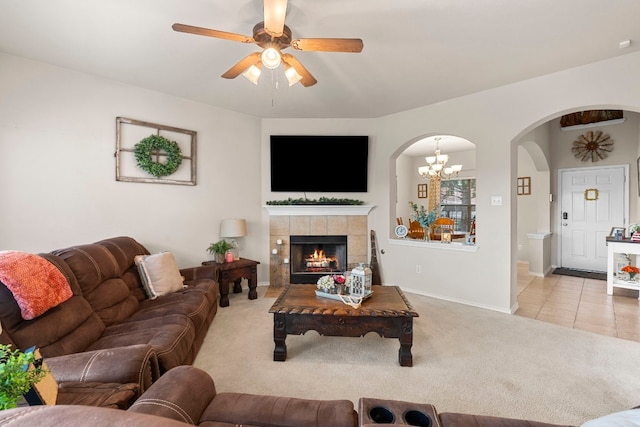 carpeted living room featuring ceiling fan with notable chandelier and a fireplace