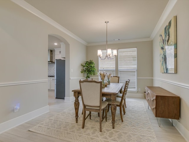 dining area with ornamental molding, light hardwood / wood-style flooring, and a notable chandelier