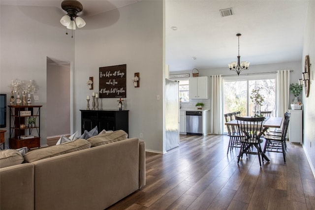 living room with ceiling fan with notable chandelier and dark wood-type flooring