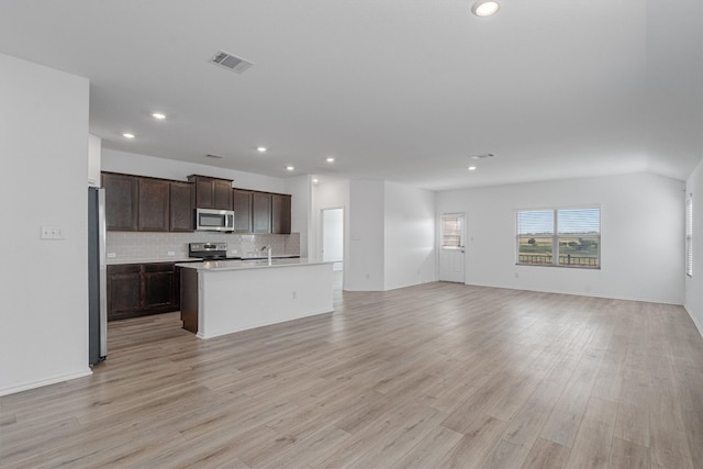 kitchen featuring an island with sink, sink, tasteful backsplash, light hardwood / wood-style flooring, and stainless steel appliances