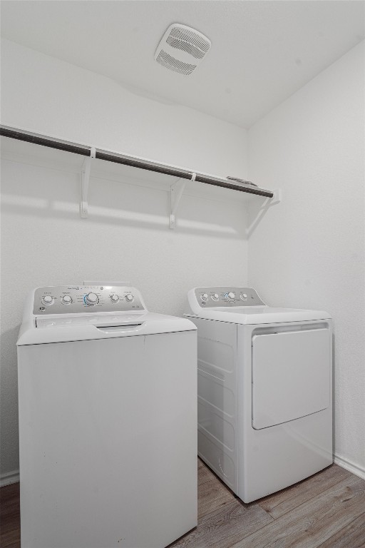 laundry room with hardwood / wood-style flooring and separate washer and dryer