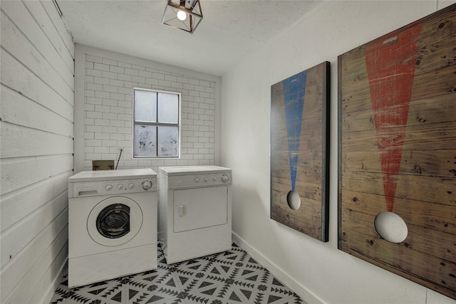 washroom featuring a textured ceiling, wooden walls, and independent washer and dryer