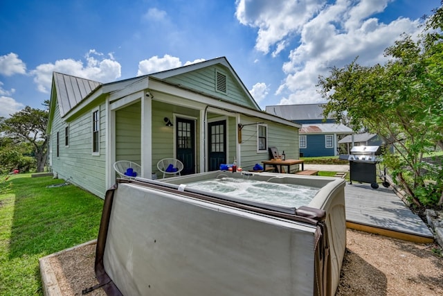 exterior space featuring a lawn, a hot tub, and a deck