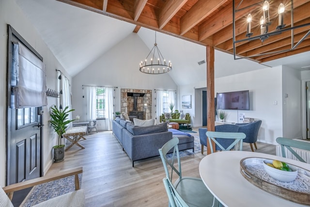 dining room featuring light wood-type flooring, beam ceiling, a fireplace, high vaulted ceiling, and an inviting chandelier