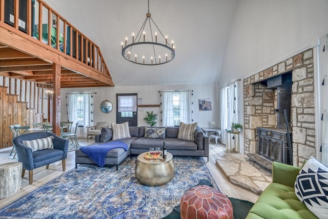 living room featuring hardwood / wood-style floors, high vaulted ceiling, a wood stove, and a notable chandelier