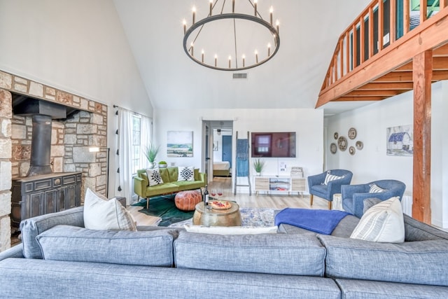 living room featuring a notable chandelier, a wood stove, high vaulted ceiling, and hardwood / wood-style floors