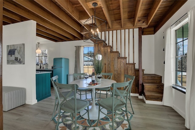 dining room with an inviting chandelier, wood-type flooring, beam ceiling, and wood ceiling