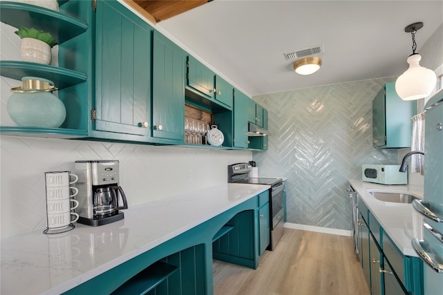 kitchen with light stone counters, sink, stainless steel range with electric cooktop, light hardwood / wood-style flooring, and decorative light fixtures