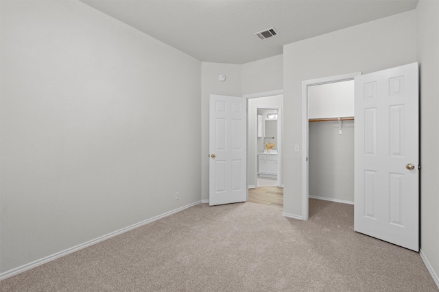 unfurnished bedroom with light carpet, a spacious closet, and a closet