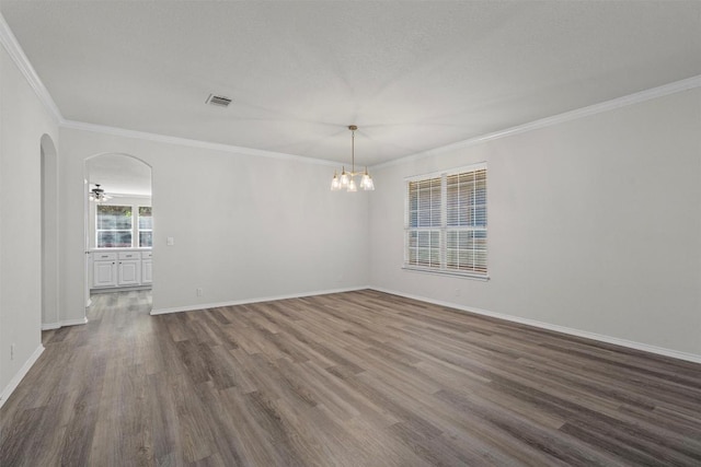 empty room featuring dark hardwood / wood-style floors, ornamental molding, and a chandelier